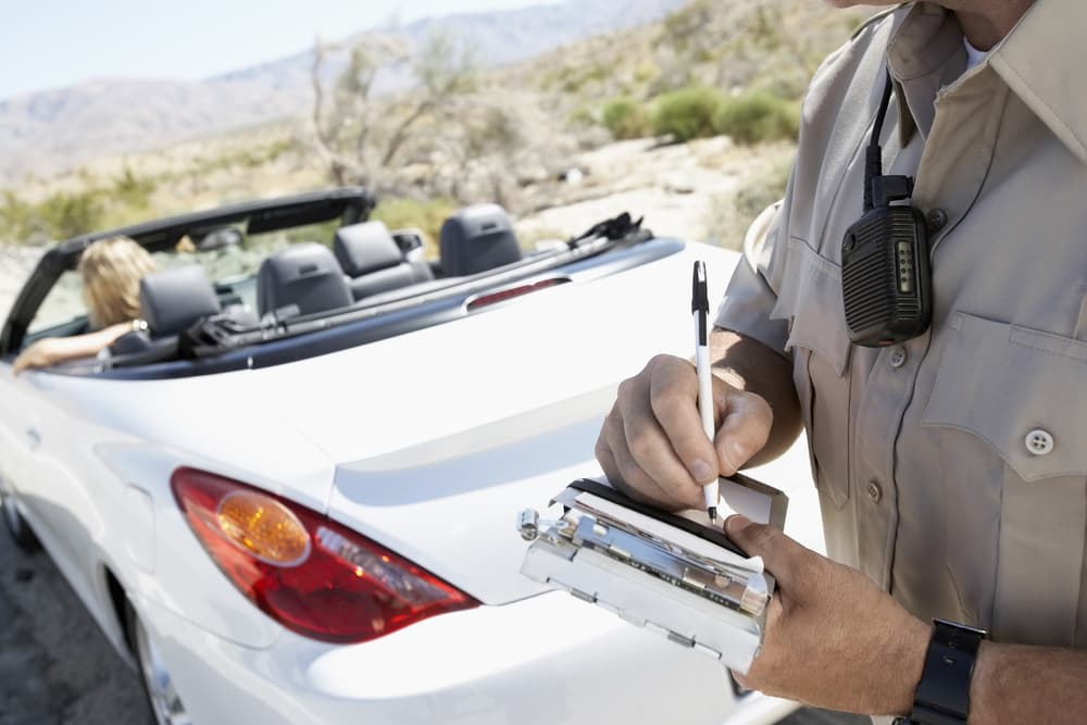 a police officer writing traffic ticket to woman sitting in car
