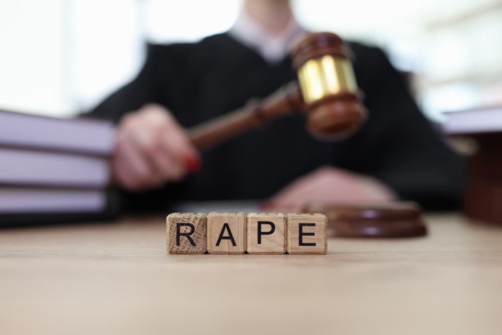 Text Rape on wooden cubes and judge with gavel in courtroom.
