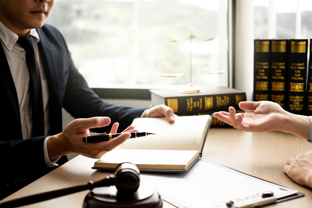 Lawyer and client sitting at a desk discussing a lawsuit, reviewing documents, and planning legal strategy together