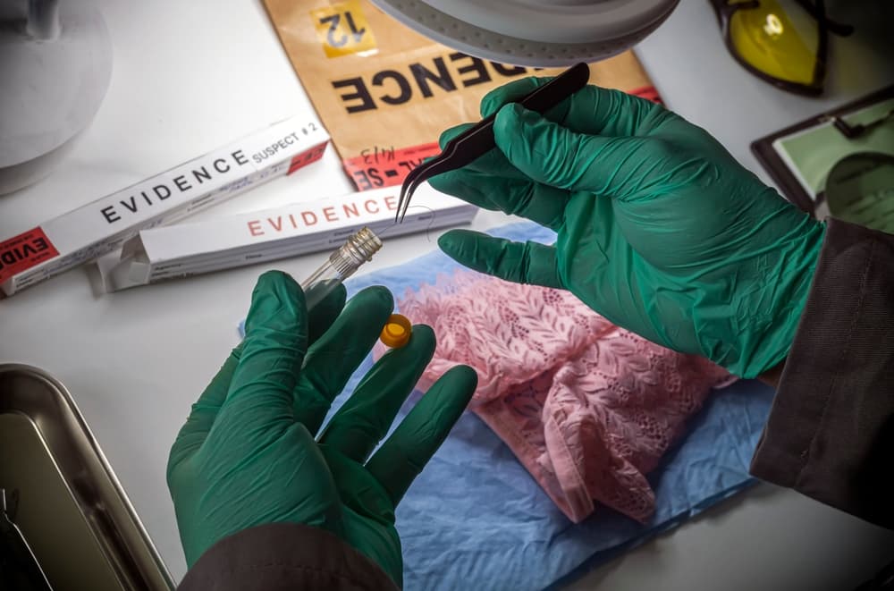 Police scientist inserts rape victim's hair into vial for crime lab DNA research,