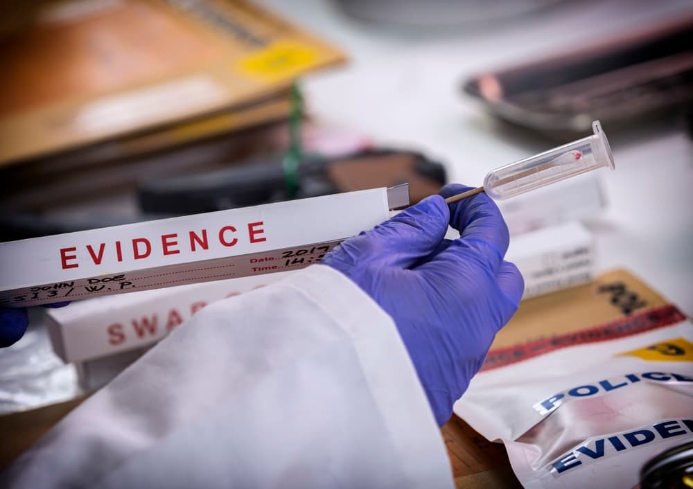 Un investigador forense sostiene un hisopo que contiene pruebas de ADN
